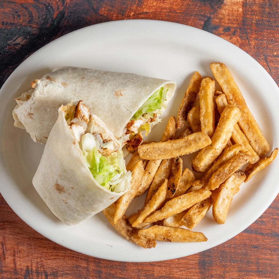 Two chicken wraps with lettuce and a side of golden french fries on a white plate.