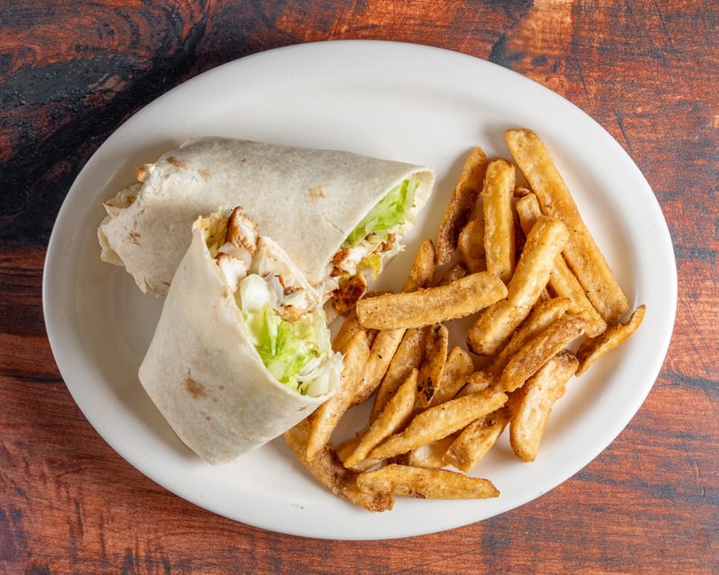 Two chicken wraps with lettuce and a side of golden french fries on a white plate.