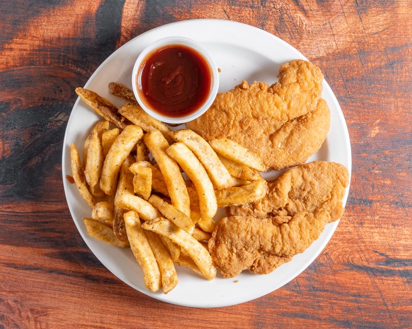 A white plate holds crispy fried chicken tenders, golden french fries, and a side of barbecue sauce.