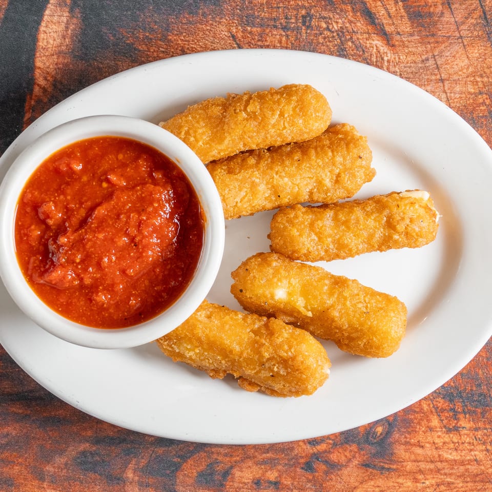 Golden-brown mozzarella sticks with a side of chunky red marinara sauce on a white plate.